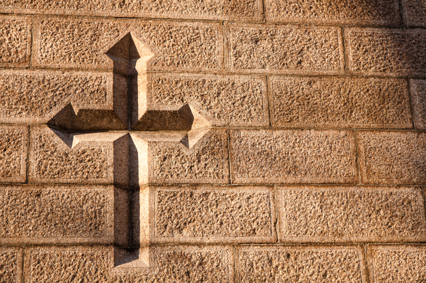 A Christian cross carved into a weathered stone wall.